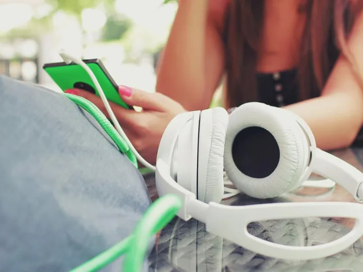 White headphones and a phone with a green case