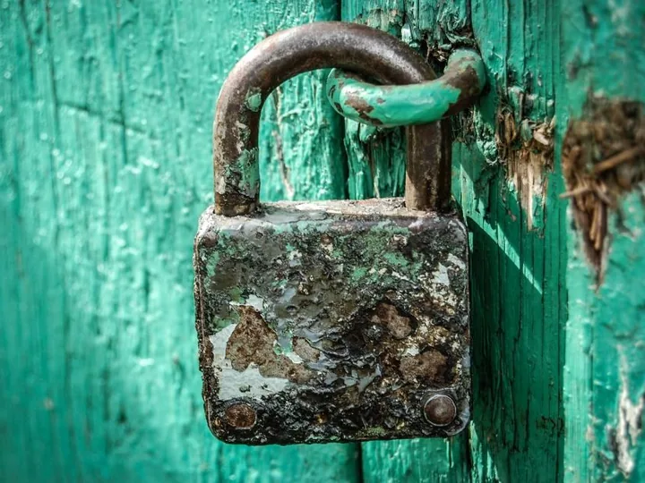 Old padlock on a teal painted wooden door